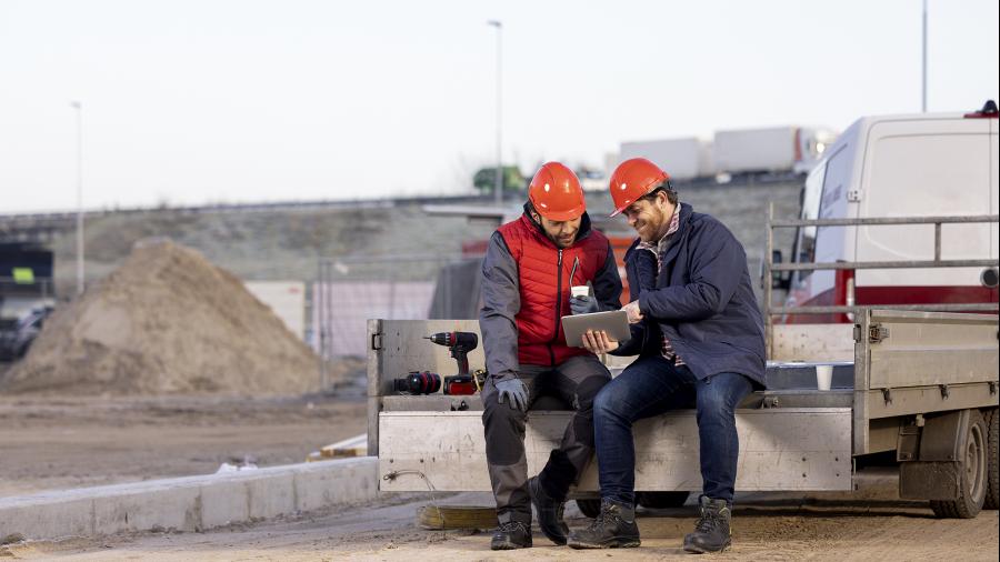 Twee mannen in de bouw spreken over iets op een tablet
